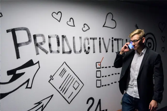 man holding smartphone looking at productivity wall decor man holding smartphone looking at productivity wall decor